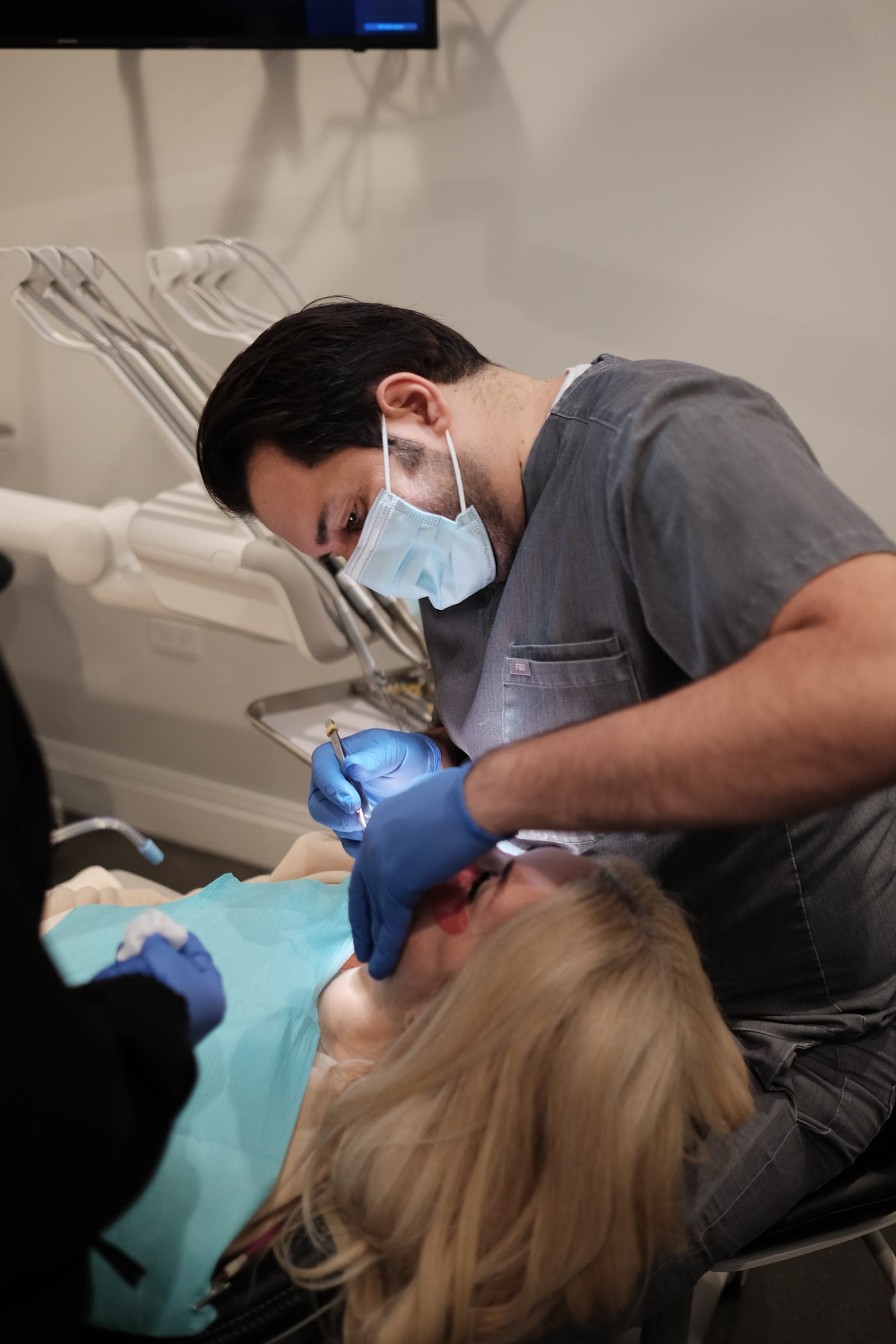 Dr. Atassi at work, masked, examining a patient